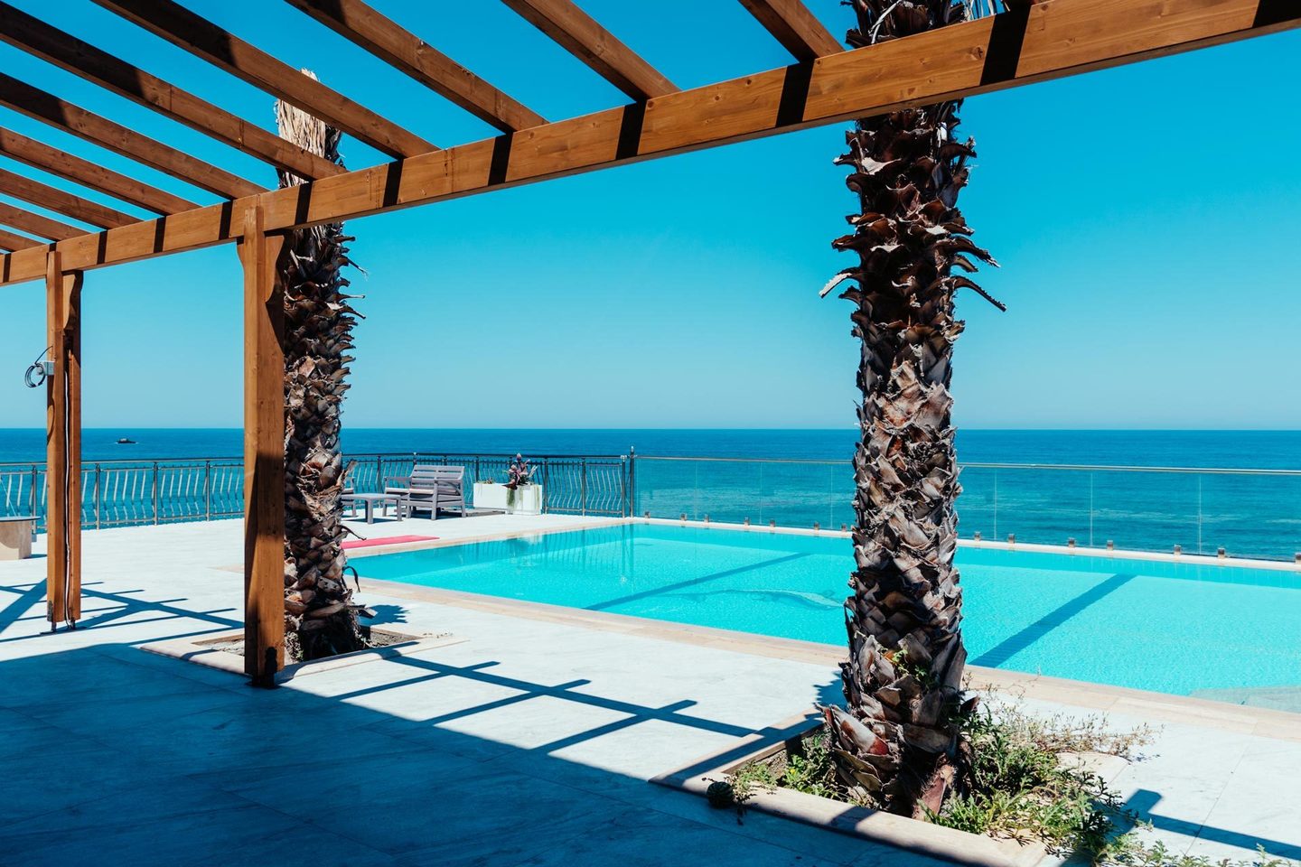 Pool mit Palmen über dem Meer